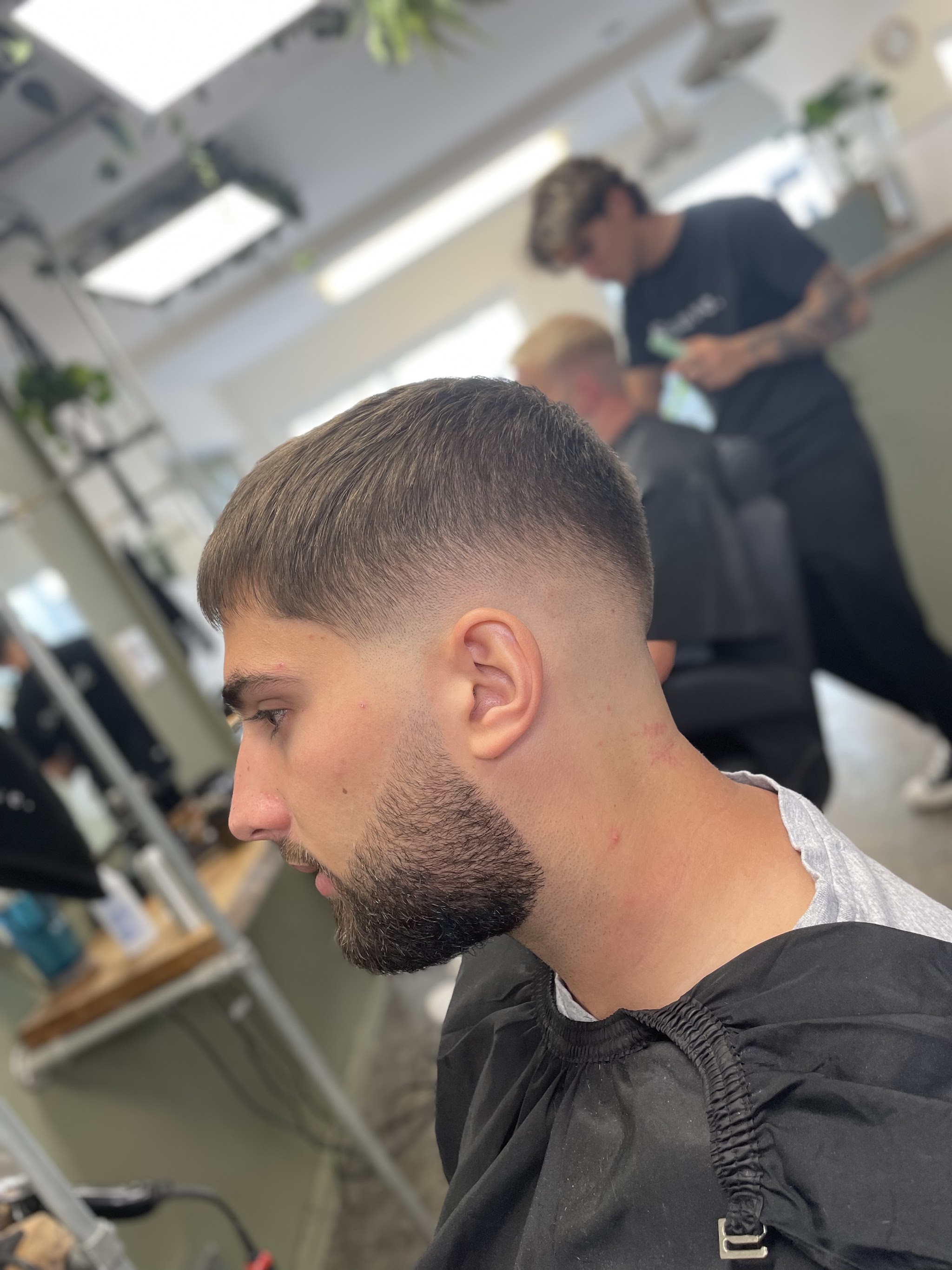 A fresh skin fade with a shaped beard, seen from the side