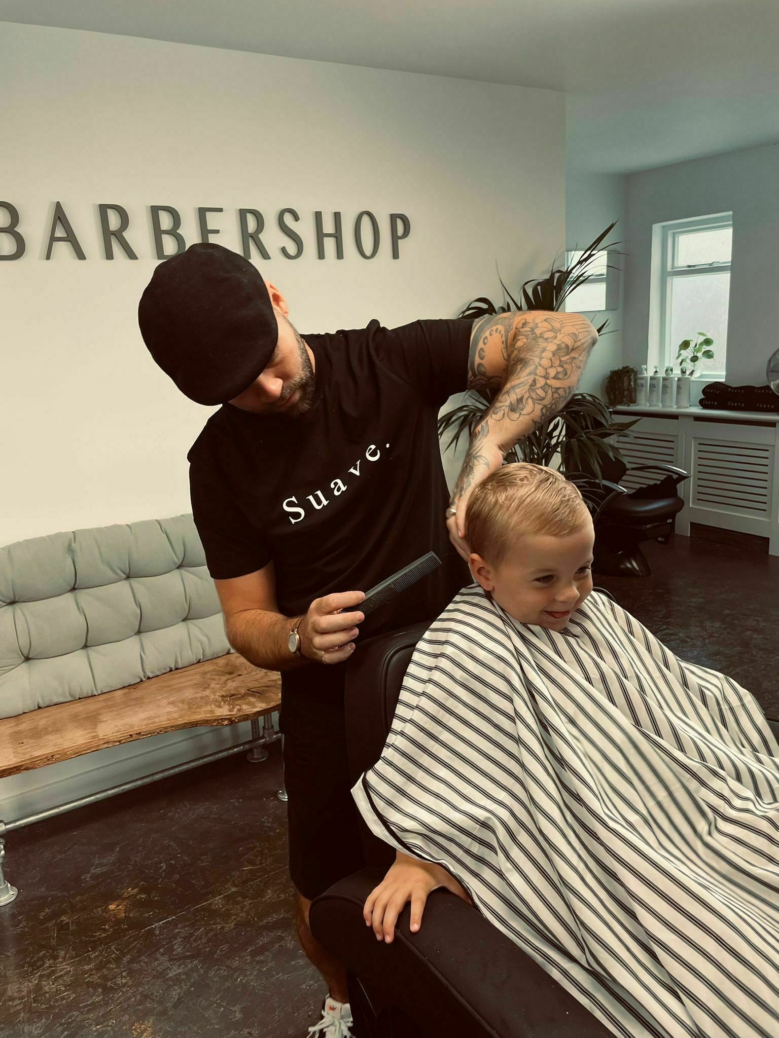 A young boy smiling in the chair while his hair is cut